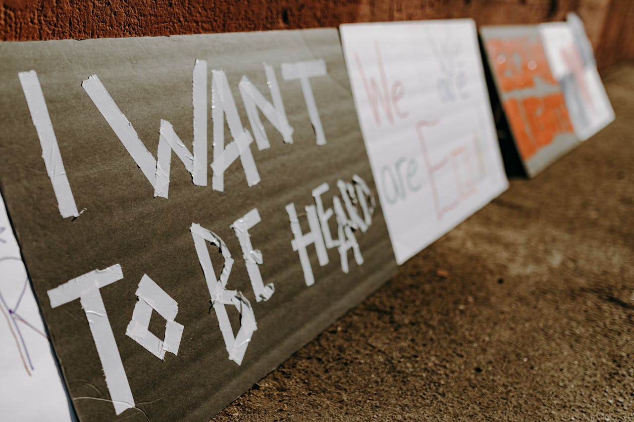 Close-up of protest signs calling for equality and justice placed on the ground.